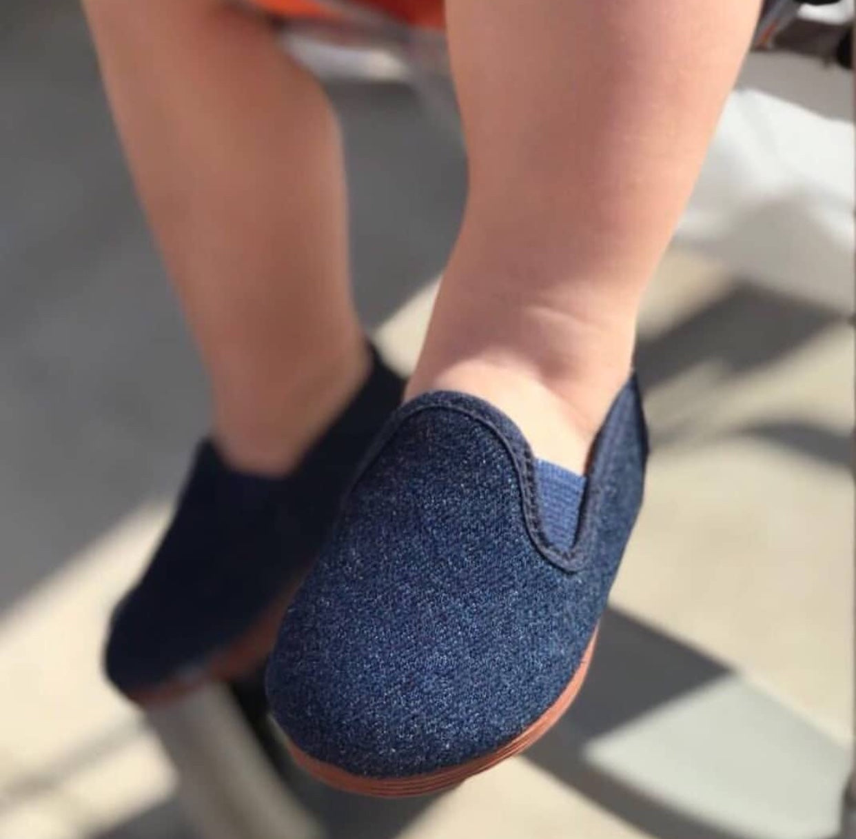 Javer Blue slip-on shoes worn by a person on a blurred outdoor background