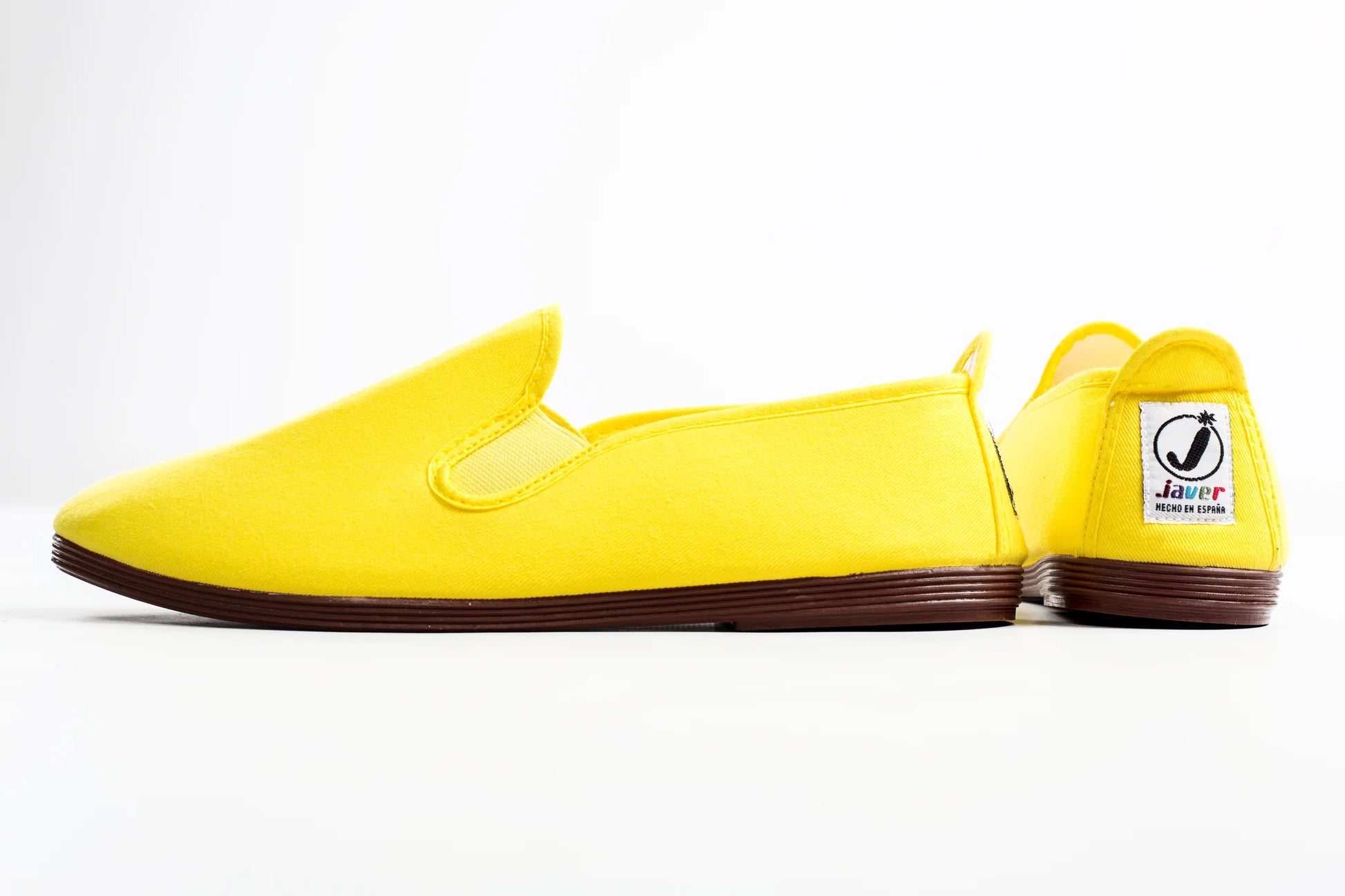 Yellow slip-on shoes with a visible brand logo on a white background