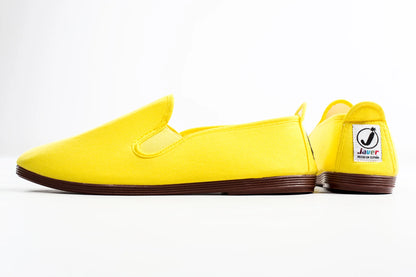 Yellow slip-on shoes with a visible brand logo on a white background